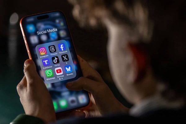 BATH, UNITED KINGDOM - FEBRUARY 23: In this photo illustration a 14-year-old boy holds an iPhone screen displaying various social media and messaging apps on February 23, 2026 in Bath, England. On top row left to right, the logo of social media platform Instagram is seen beside that of Meta’s Threads and Facebook. On the middle row from left is the logo of Donald Trump's Truth Social app, next to the logo of social media app TikTok and the logo of Elon Musk’s US online social media and social networking site 'X' (formerly known as Twitter). Along the bottom row, left to right is the messaging service WhatsApp, the logo for online video sharing and social media platform YouTube and the logo for the Bluesky app. In the UK, a ban on social media for under-16s has been backed by the House of Lords following the Australian law which aims to stop children under 16 from having social media accounts and social media platforms, including TikTok, Facebook, Snapchat, Reddit, X, formerly Twitter, and Instagram potentially being be fined for preventing children younger than 16 from having social media accounts. (Photo by Anna Barclay/Getty Images)