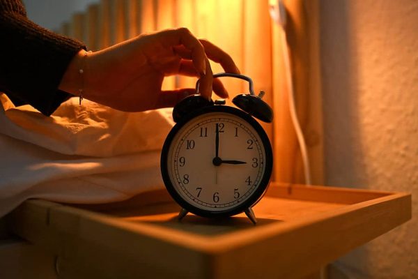 ILLUSTRATION - 19 March 2026, Berlin: A woman reaches for an alarm clock next to her bed. Daylight saving time begins in Germany on 29.03.2026. Photo: Elisa Schu/dpa (Photo by Elisa Schu/picture alliance via Getty Images)