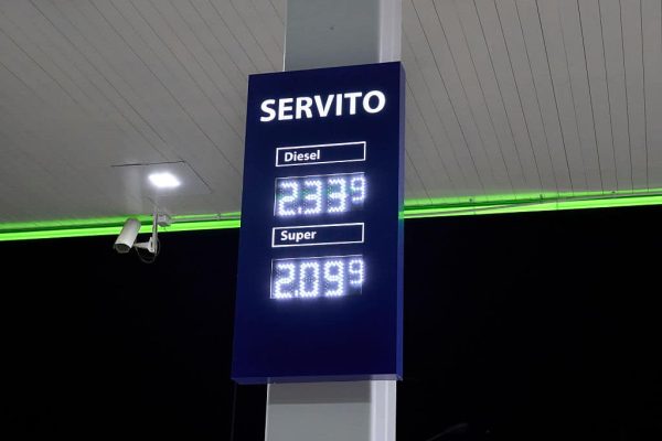 A full-service price board displaying 2.339 euros per liter for diesel and 2.099 euros for petrol is illuminated at night at a filling station in Barletta, Italy, on August 16, 2026. A security camera is mounted beneath the canopy beside the sign, with a green neon strip lighting the ceiling above. Full-service prices in Italy are typically higher than self-service rates because they include the cost of pump attendants, during a summer marked by elevated fuel costs nationwide. (Photo by Matteo Della Torre/NurPhoto via Getty Images)